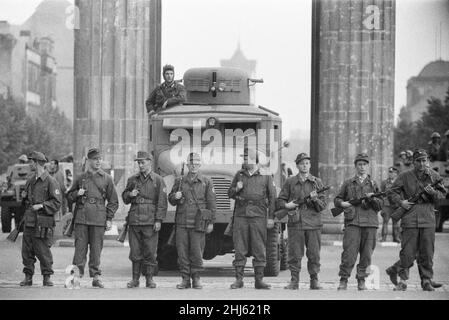 Inizio della costruzione del Muro di Berlino.a mezzanotte il 13th agosto la polizia e le unità dell'esercito tedesco orientale iniziarono a chiudere il confine e, entro domenica mattina, il 13 agosto, il confine con Berlino Ovest fu chiuso. La foto scattata tre giorni dopo mostra: I compagni dei gruppi di combattimento della classe operaia, impiegati per proteggere il confine, si trovano pronti presso la porta di Brandeburgo, protetta da un veicolo armato scout della polizia di frontiera. Il sito è stato visitato dal sindaco di Berlino Ovest Willy Brandt e dai generali dell'esercito americano. 16th agosto 1961. Foto Stock