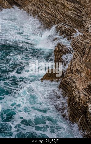 Sfondo marino spettacolare. Costa rocciosa del Mare Adriatico. Le onde bianche e schiumose battono contro la riva di pietra. Panorama della costa marina. Vista dall'alto dell'antenna. Adriatico Foto Stock