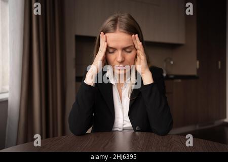 Freelancer femminile caucasico malsano con massaggio della testa touch che soffre di emicrania sul posto di lavoro domestico. Capogiri o cefalea. Giovane dipendente malato Foto Stock