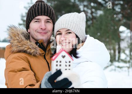 Uomo e donna in amore outdoor data in inverno con simbolo di casa e amore. San Valentino, coppia felice, storia d'amore. Nido d'amore, ipoteca, delocalizzazione, Foto Stock