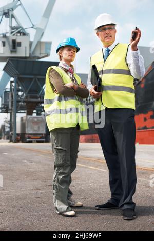 Una comunicazione efficace tra i colleghi è fondamentale. Due ingegneri discutono della pianificazione in un sito mentre si trovano nel cantiere. Foto Stock