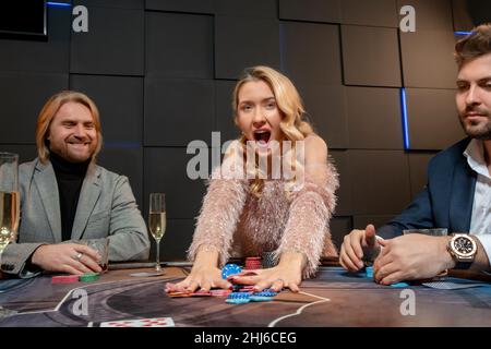 Donna felice eccitato vincendo gioco di poker rastrellare chip di gioco Foto Stock