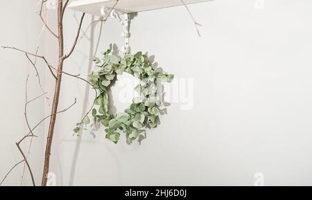 corona di rami eucaliptus appesa a una parete, decorazioni primaverili in una casa in stile rustico. decorazione stagionale per vacanze primaverili. spazio copia Foto Stock