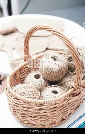 palle di crochet di iuta e rocche di fili in un cestino sul tavolo. hobby e artigianato. materiali ecologici per maglieria. Foto Stock