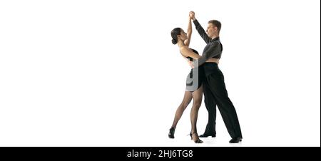 Volantino con giovane coppia di ballerini che ballano tango argentino isolato su sfondo bianco studio. Artisti in costumi da palcoscenico nero Foto Stock