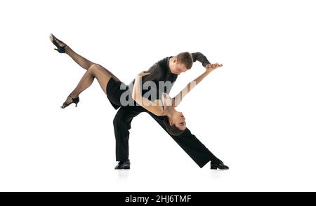 Bello sportivo giovane uomo e donna che ballano tango argentino isolato su sfondo bianco studio. Artisti in costumi da palcoscenico nero Foto Stock