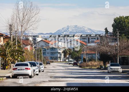Side, Turchia -20 gennaio 2022: Strada della città con diverse case basse, parcheggio auto e montagna sullo sfondo Foto Stock