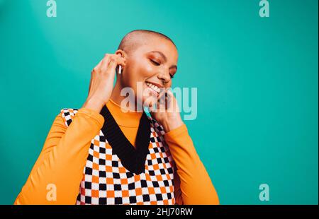 Donna che ascolta musica felice in uno studio. Spensierate la giovane donna sorridendo e toccando le sue cuffie wireless mentre ascolti la musica. Giovane donna enj Foto Stock