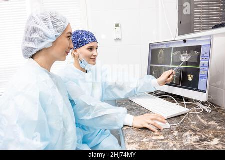 Concetto di odontoiatria. Servizi dentistici professionali e attrezzature moderne senza dolore. Il medico consulta il paziente e visualizza le immagini di Foto Stock