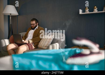 Un uomo d'affari che lavora su un notebook dimentica del ferro da stiro Foto Stock