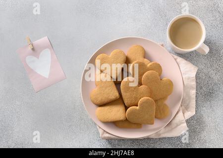 Biscotti a forma di cuore su piatto rosa con caffè e regalo per San Valentino. Vista dall'alto. Foto Stock