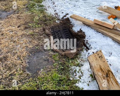 Pneumatici auto battistrada piedi in primavera. Ingombro pneumatico bloccato per auto, con tavole di legno accanto ad esso. Prato. Script. Sfondo marrone astratto. Piede della ruota dell'auto Foto Stock