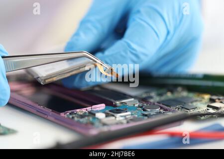 Master repairman che inserisce il microchip nel primo piano dei telefoni cellulari Foto Stock