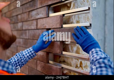 Pietra di rivestimento del lavoratore per il riscaldamento della parete esterna Foto Stock