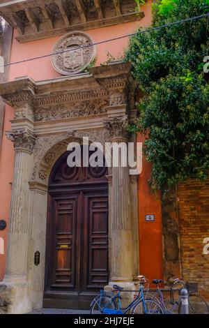 Bella porta in legno nell'arco attraverso parete arancione primo piano con una tre e una bicicletta. Esterno dell'edificio, facciata Foto Stock