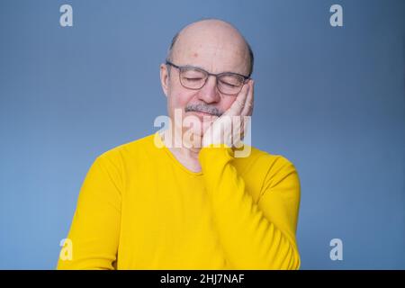 Uomo anziano in occhiali che dormono stanco sognando sorridendo a occhi chiusi. Foto studio Foto Stock