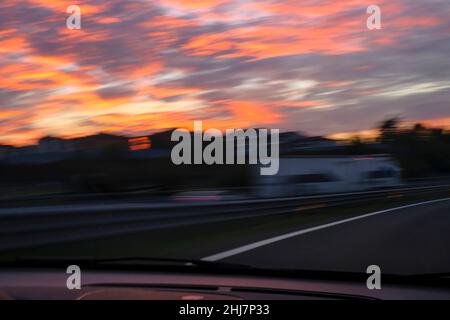 Tramonto sfocato sull'autostrada piena di auto attraverso il ponte e cielo pieno di nuvole. Viaggio, concetto avventuroso Foto Stock