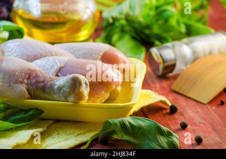 bastone di pollo crudo e spezie sul tavolo Foto Stock