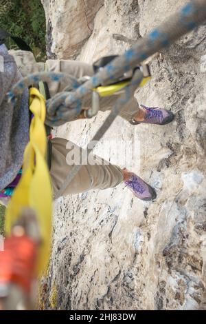 POV: Scalatore di roccia appende dalla corda e dall'ingranaggio alto sopra il terreno Foto Stock