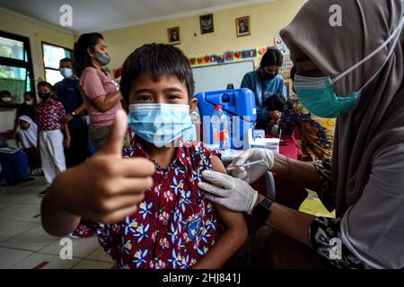 Tangerang Sud, Provincia di Banten. 27th Jan 2022. Un operatore sanitario somministra una dose di vaccino COVID-19 a un bambino durante una campagna di vaccinazione per bambini di età compresa tra 6 e 11 anni nel villaggio di Serua a South Tangerang, provincia di Banten, Indonesia. 27 gennaio 2022. Credit: Agung Kuncahya B./Xinhua/Alamy Live News Foto Stock