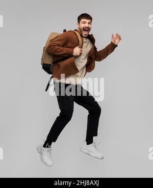 sorridente ragazzo con zaino che salta in aria Foto Stock