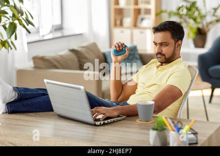 uomo con notebook e espansore a mano in ufficio a casa Foto Stock