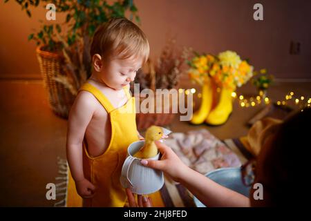 bambino in tuta gialla con oca per pasqua Foto Stock