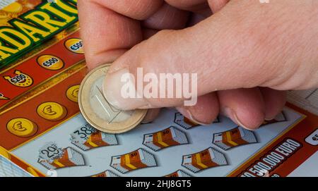 mano di una donna che graffia un biglietto istantaneo della lotteria con una moneta da un euro Foto Stock