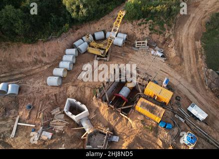 Tubi fognari in calcestruzzo per la posa di sistemi fognari esterni in cantiere. Alesatrice a tunnel in collettore fognario per costruzioni sotterranee Foto Stock