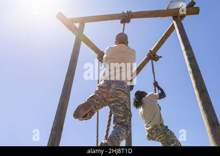 Due soldati maschi afroamericani arrampicano su corda durante il corso di ostacoli al campo di stivali Foto Stock