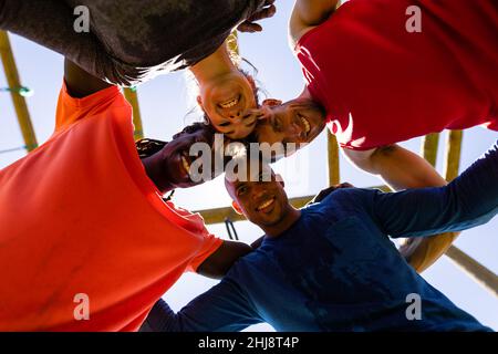Vista ad angolo basso di gruppo di diverse persone in forma maschile e femminile che formano capoddle al campo di stivali Foto Stock