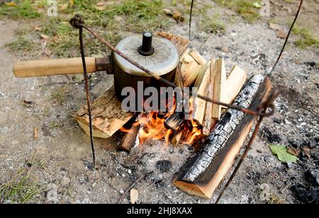 Acqua bollente su carboni rossi caldi nella foresta. Fai la cottura del fuoco. Falò per scaldare acqua o cibo durante il campeggio in natura. Campeggio nella fauna selvatica. Cottura o Foto Stock