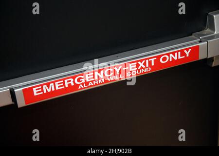 Solo uscita di emergenza parete di allarme premere maniglia su una porta di sicurezza nera in uno spazio industriale Foto Stock