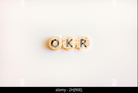 OKR, simbolo obiettivi e risultati chiave. Parole chiave OKR obiettivi e risultati chiave su cerchi di legno su uno splendido sfondo bianco. Business OKR o Foto Stock