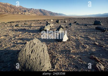 Ventifacts, scolpito da sabbia e polvere soffiata dal vento, Death Valley National Park, California, USA. Montagne nere delimitate da difetti sullo sfondo. Foto Stock