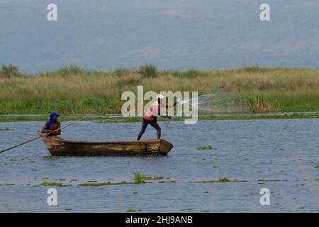 Pescatori sul Nilo Uganda- piccola barca da pesca sul Nilo vicino a Hippos, un pescatore che getta una rete per l'acqua Foto Stock