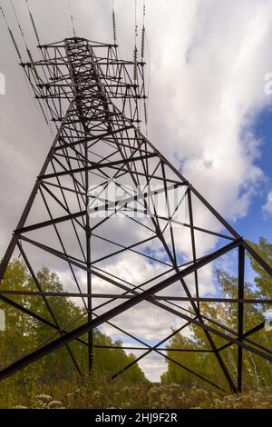 Il pilone di trasmissione dell'elettricità di fronte al cielo blu nuvoloso in estate. Apparecchiature elettriche ad alta tensione. Foto Stock