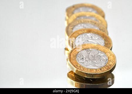 Primo piano di una colonna di monete da una libbra isolate su un semplice sfondo bianco. Nessuna gente. Spazio di copia. Foto Stock