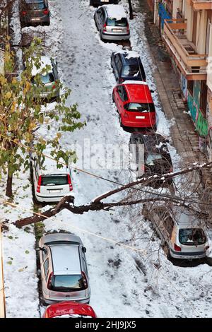 Vista aerea delle auto parcheggiate durante una giornata di neve nel distretto di Exarchia, Atene, Grecia, nel gennaio 24th 2022, mentre un albero è pronto a cadere per la strada Foto Stock