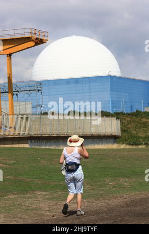 Donna che cammina oltre Sizewell centrale nucleare Suffolk Inghilterra UK Foto Stock