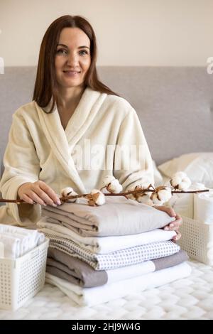 Mani donna ben curate che tengono il ramo di cotone con pelo di lenzuola e coperte ripiegate Foto Stock