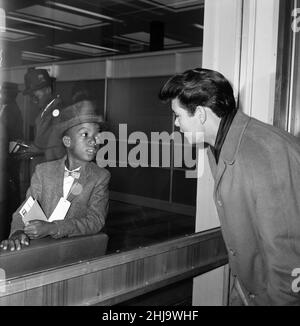 Cliff Richard e The Shadows all'aeroporto di Londra. Questo piccolo ragazzo giamaicano ha appena volato dentro da Kingston Jamaica. Il primo inglese che vede all'atterraggio è Cliff Richard, e lo guarda attraverso la finestra nella sala immigrazione. 30th ottobre 1962. Foto Stock