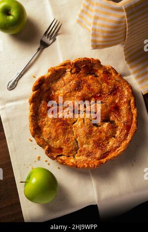 Una torta di mele casalinga calda e hanksgiving con una forchetta seduta su un rustico tavolo di legno. Foto Stock