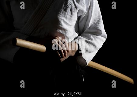 Aikido hakama, divisa per arti marziali giapponesi su sfondo nero. Profondità di campo poco profonda. SDF. Una ragazza in hakama nero in piedi in posa di combattimento con w Foto Stock
