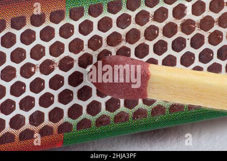Vista ravvicinata della testa di un match stick che sta per essere illuminata contro una scatola di match Foto Stock