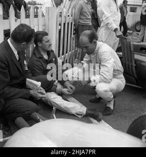 Gare automobilistiche a Goodwood. Il pilota di corse ACE Stirling Moss ha avuto una fuga miracolosa dalla morte quando si è schiantato a 120 miglia all'ora. Nella foto, Moss chiacchierava con Graham Hill immediatamente prima della gara che Hill vinse, e Moss si schiantò. 23rd aprile 1962. Foto Stock