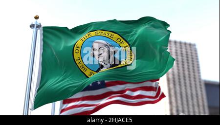 La bandiera dello stato americano di Washington sventola nel vento con la bandiera americana offuscata sullo sfondo. Washington è uno stato nel nord del Pacifico Foto Stock