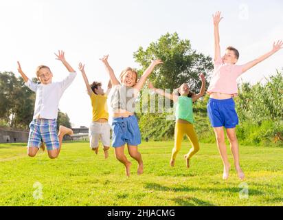 I bambini saltano e alzano le mani Foto Stock