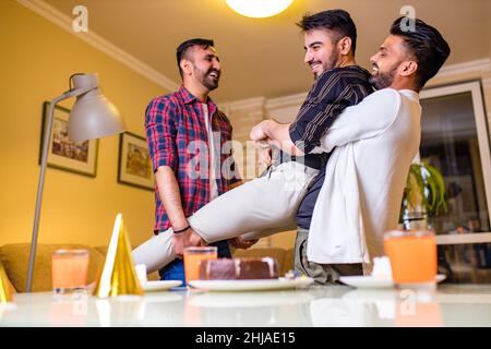 L'uomo arabo eccitato pronto a soffiare le candele sulla torta in festa di compleanno con gli amici felici nella casa Foto Stock