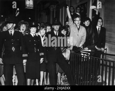 I fan dei Beatles sono stati raffigurati dietro gli ufficiali di polizia fuori dal London Palladium, dove il gruppo si esibisce questa sera nella "serata di giorno al London Palladium" della BBC-TV. 13th ottobre 1963. Foto Stock